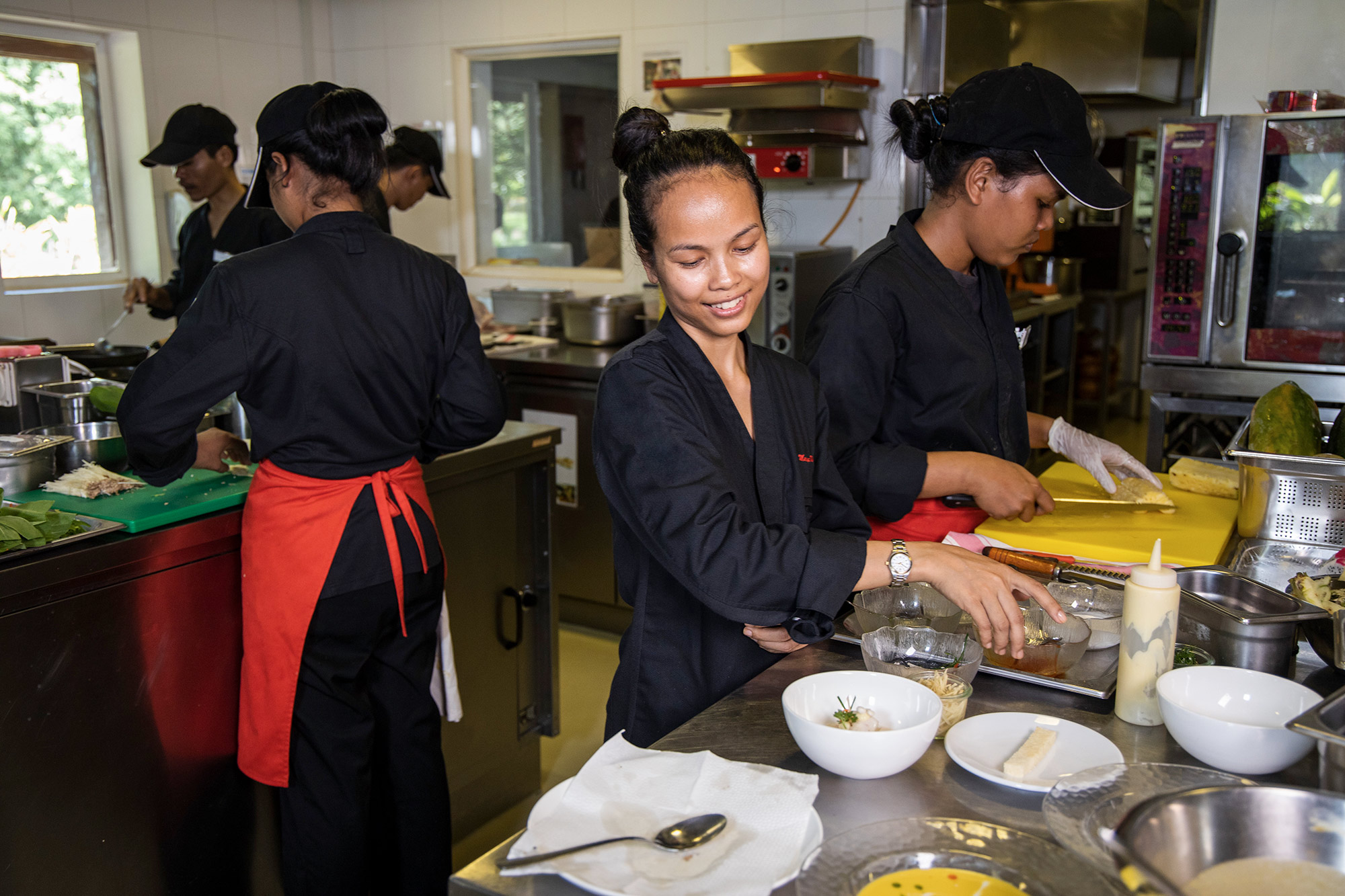 Mariya Un Noun prepares food with her team in the kitchen.