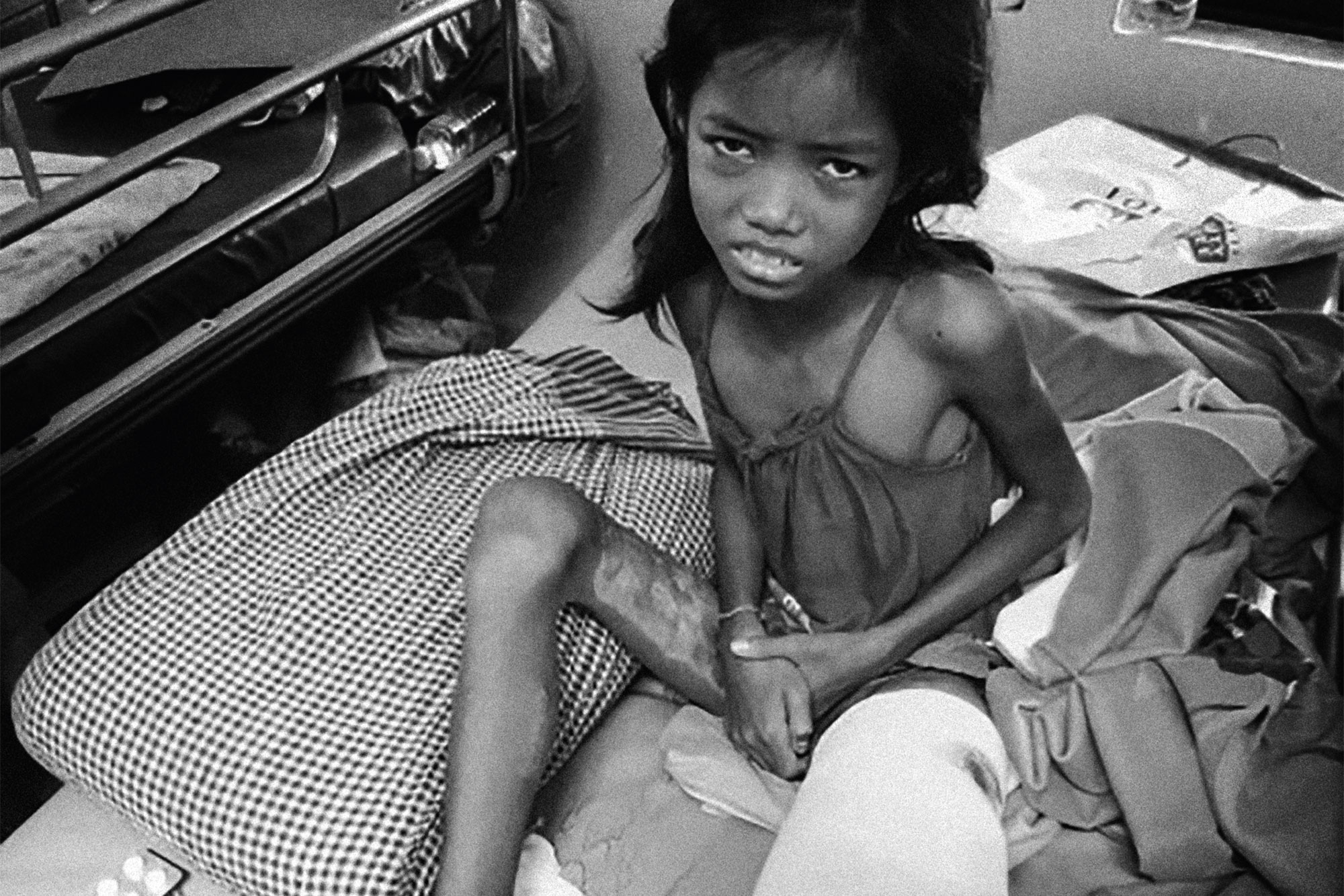 A girl sits beside a bed in a treatment room.