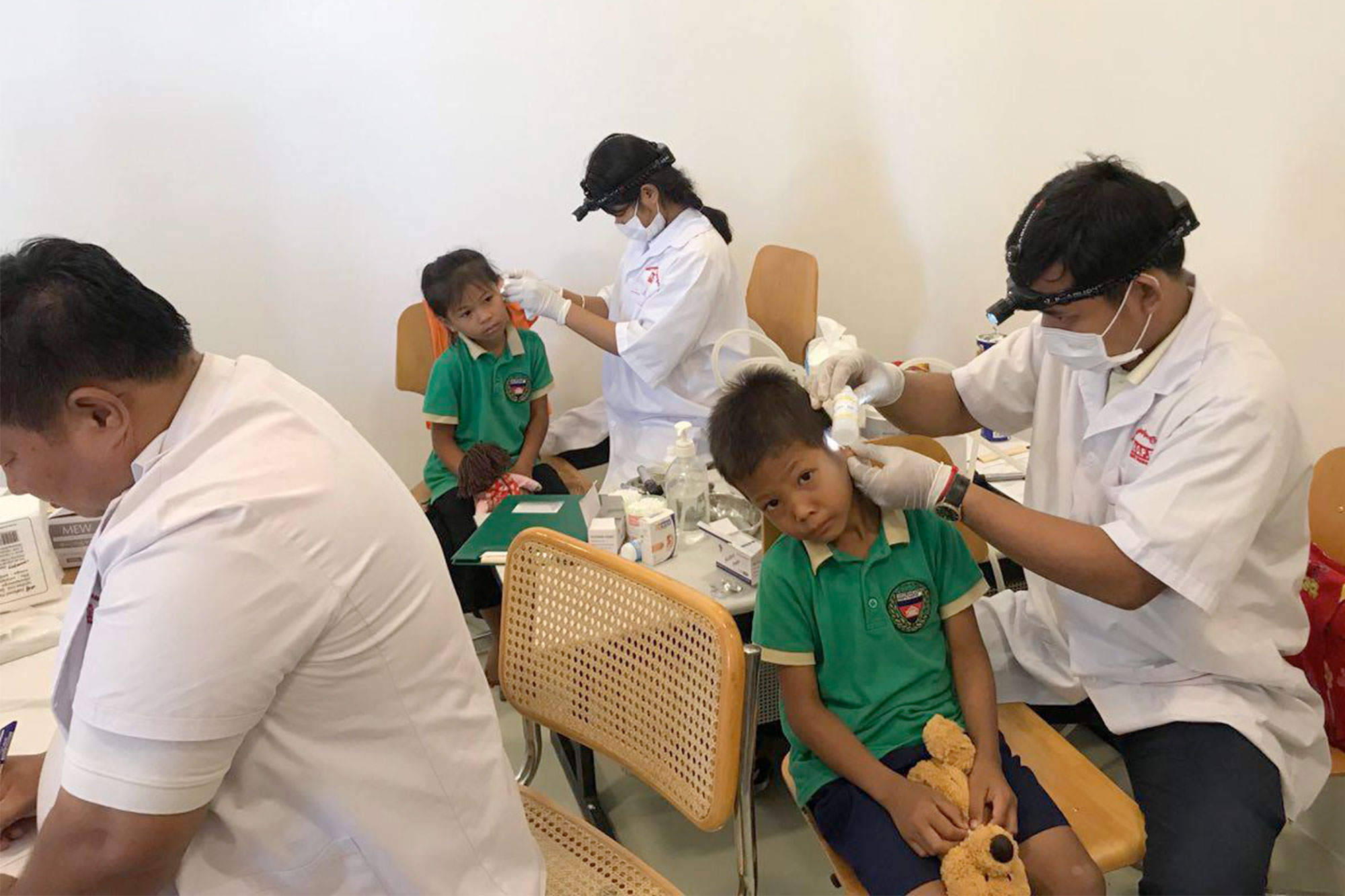 A medical team examines children in a treatment room.