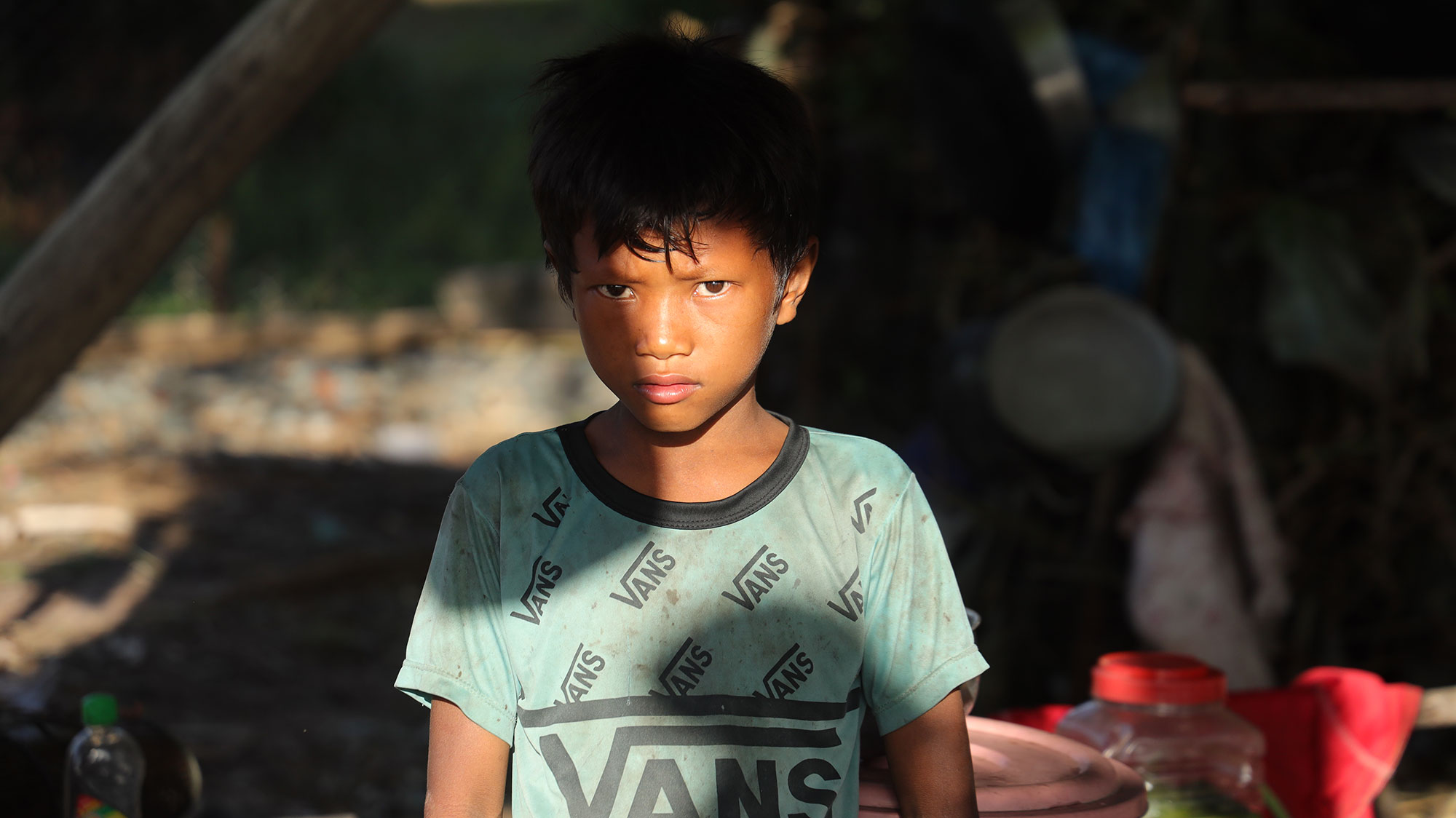 Portrait d’un garçon en tee-shirt vert devant son abri.