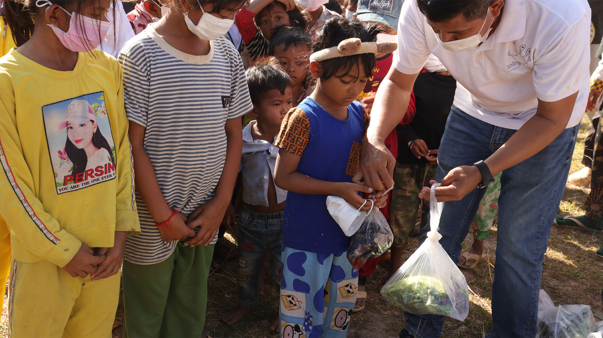 Un bénévole distribue des produits de première nécessité à des enfants qui attendent.
