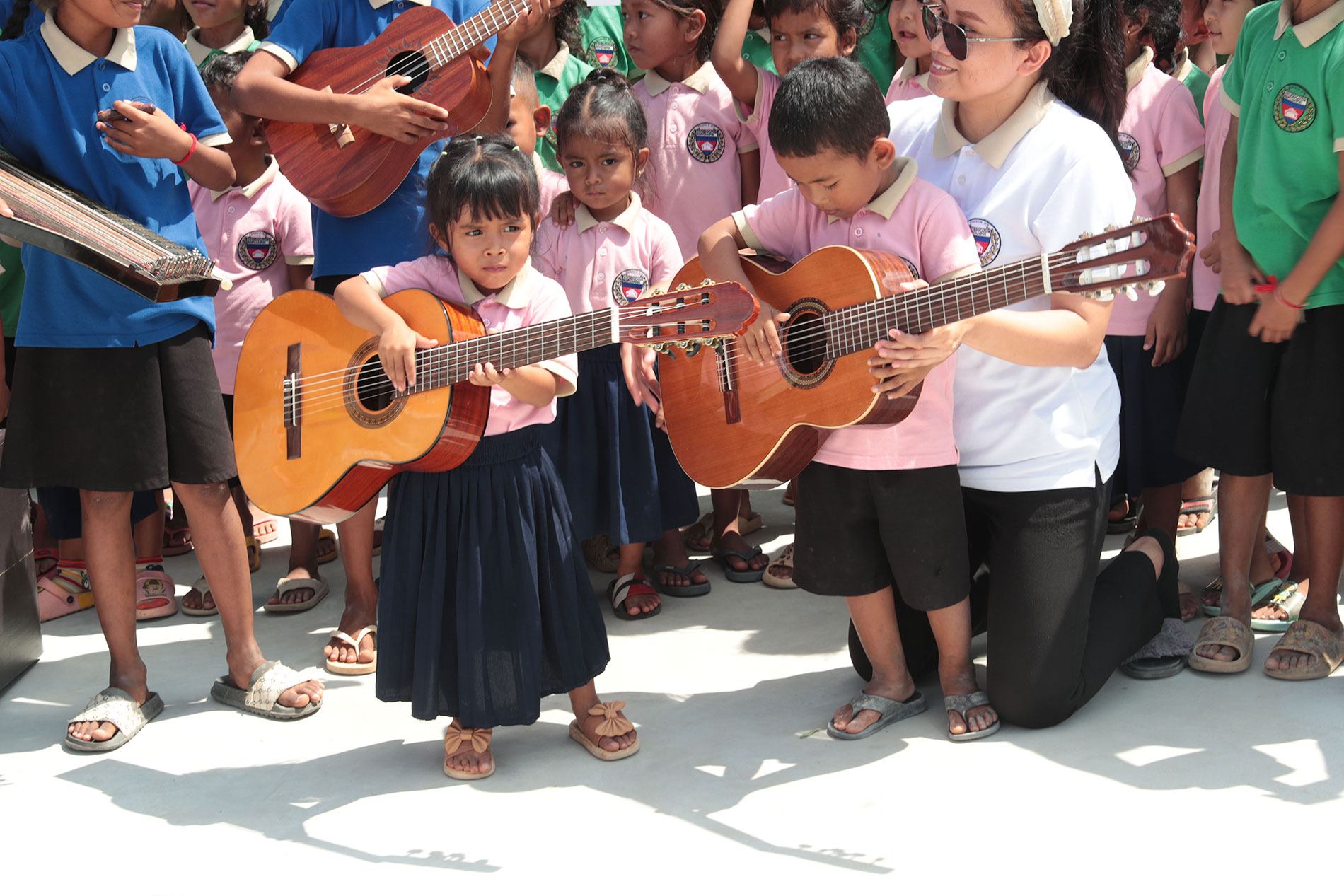Kinder halten Gitarren bei der Übergabe der Musikinstrumente.
