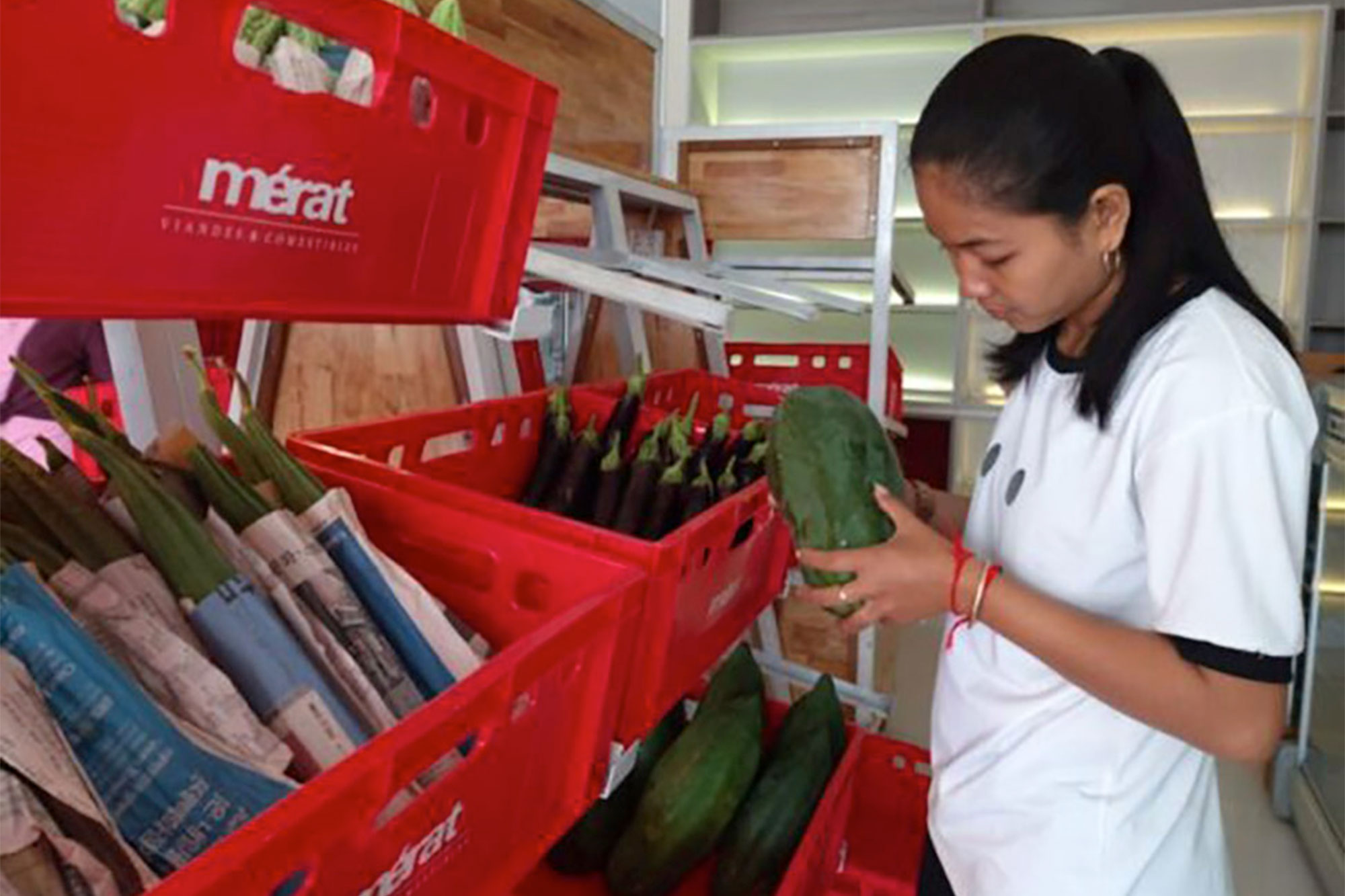 Une employée examine des légumes dans le Farmhouse Shop.