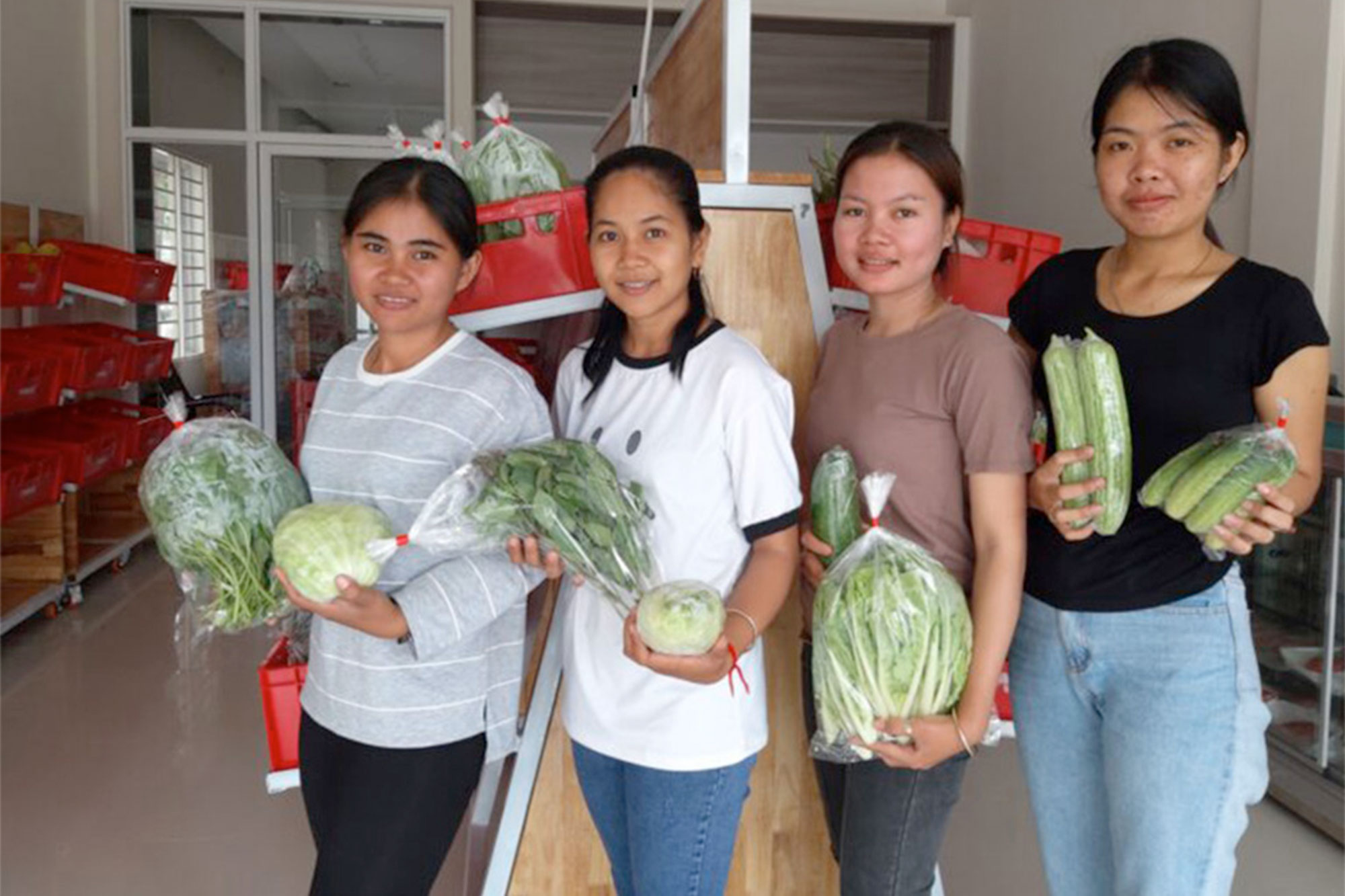 Quatre femmes présentent des légumes frais dans le Farmhouse Shop.
