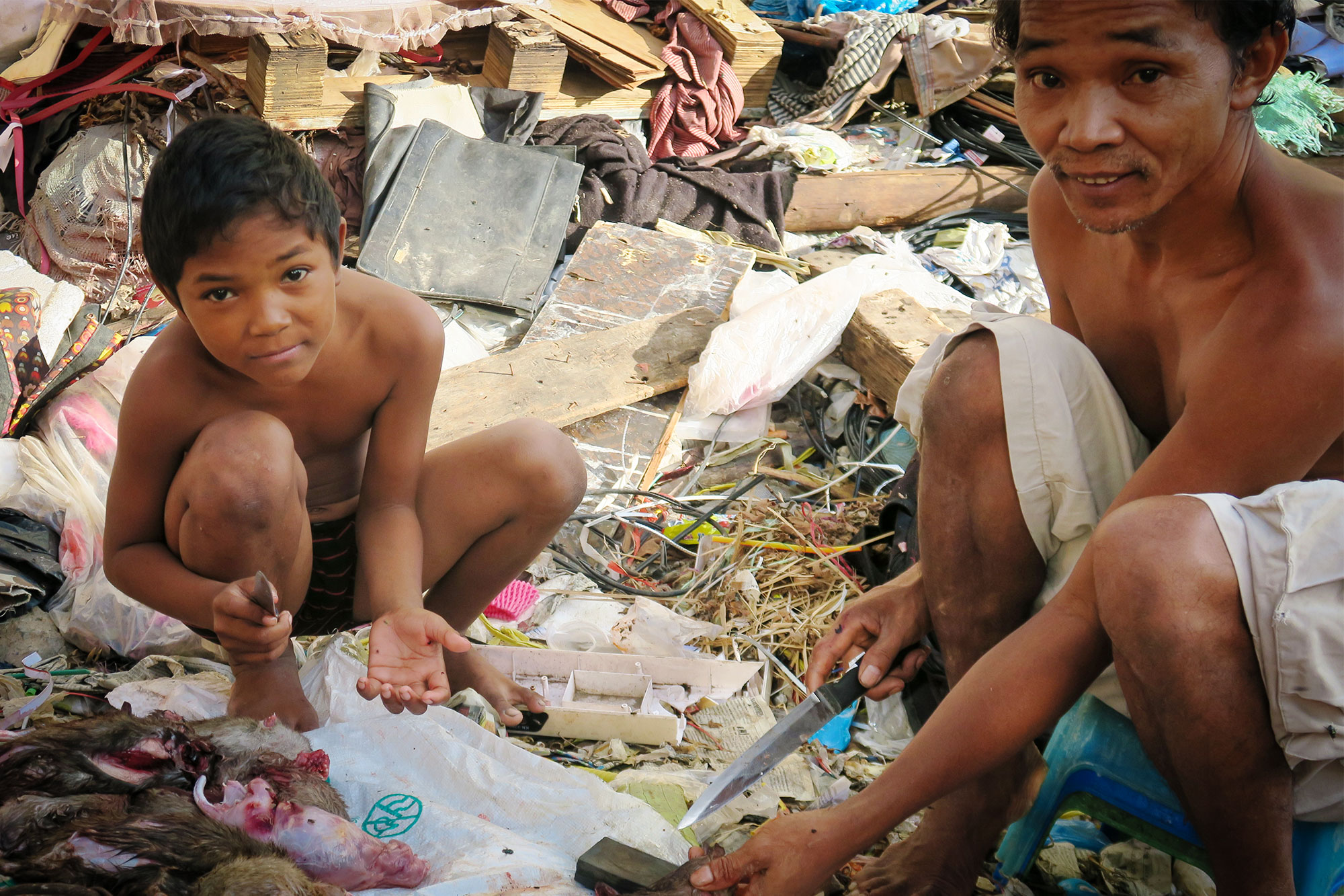 A man and a boy preparing caught rats.