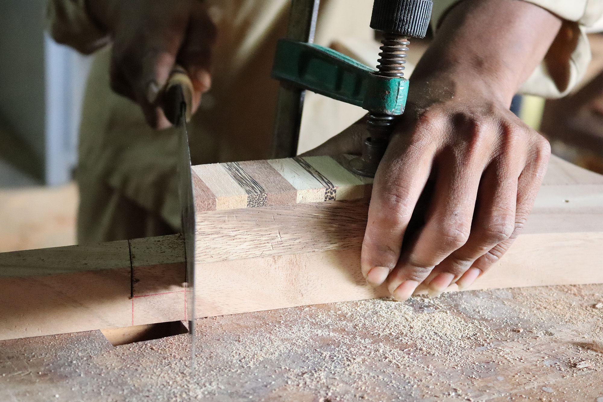 Des mains fixent une pièce de bois avec un serre-joint.