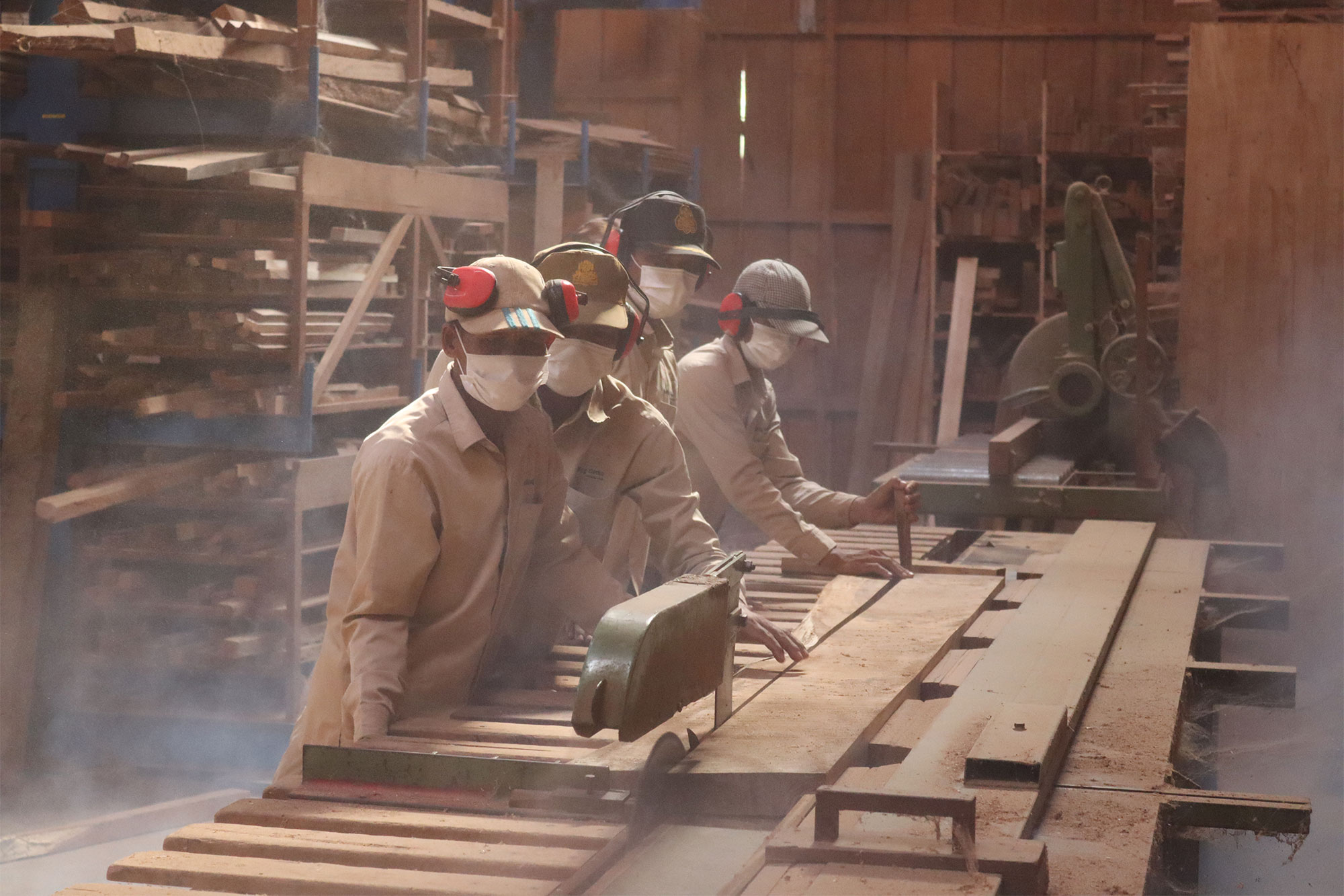 Des menuisiers travaillent de longues planches sur une machine.