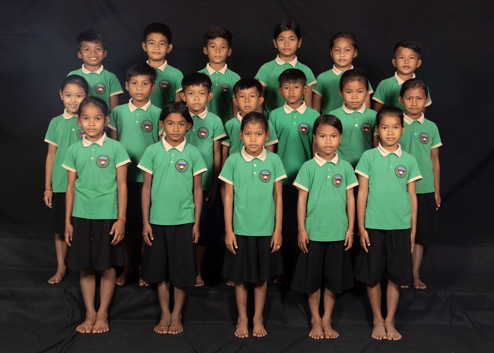 Group portrait of children in green school uniforms.