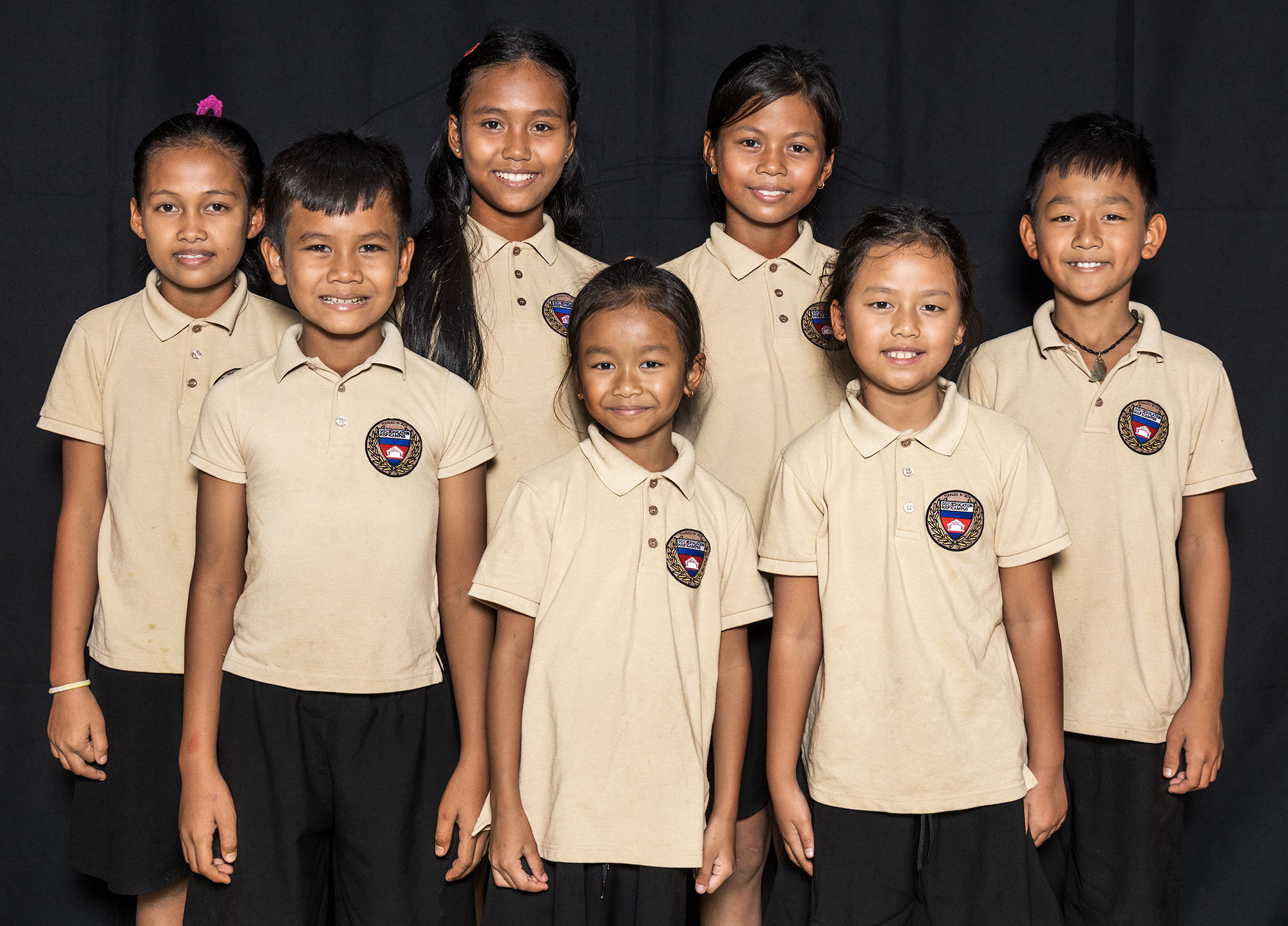 Schoolchildren wearing matching light-coloured polo shirts.