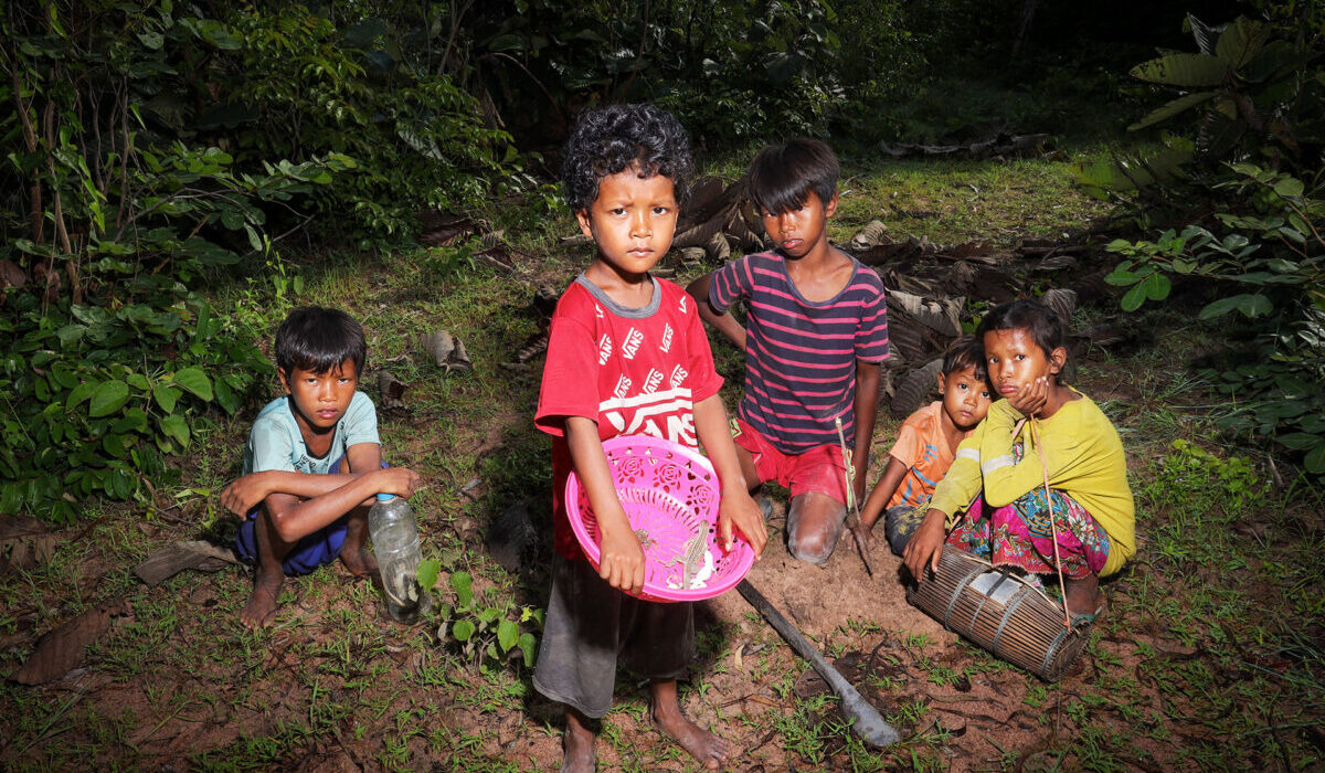 Four children outdoors with a bowl and a tool.