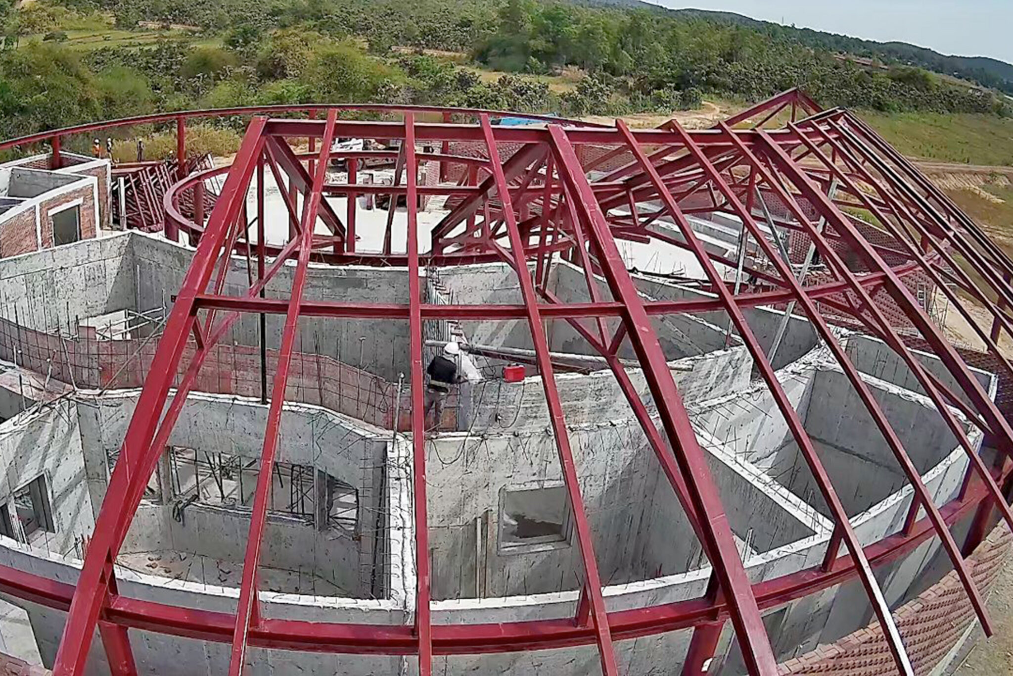 Blick von oben auf rote Dachträger und Betonwände eines Gebäudes im Bau.