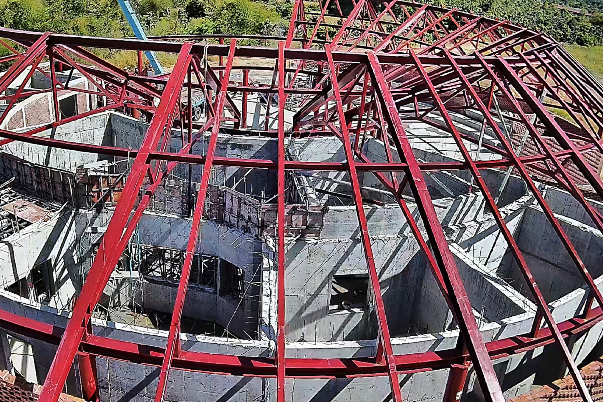 Rote Stahlträger überspannen die Innenwände eines runden Gebäudes im Bau.