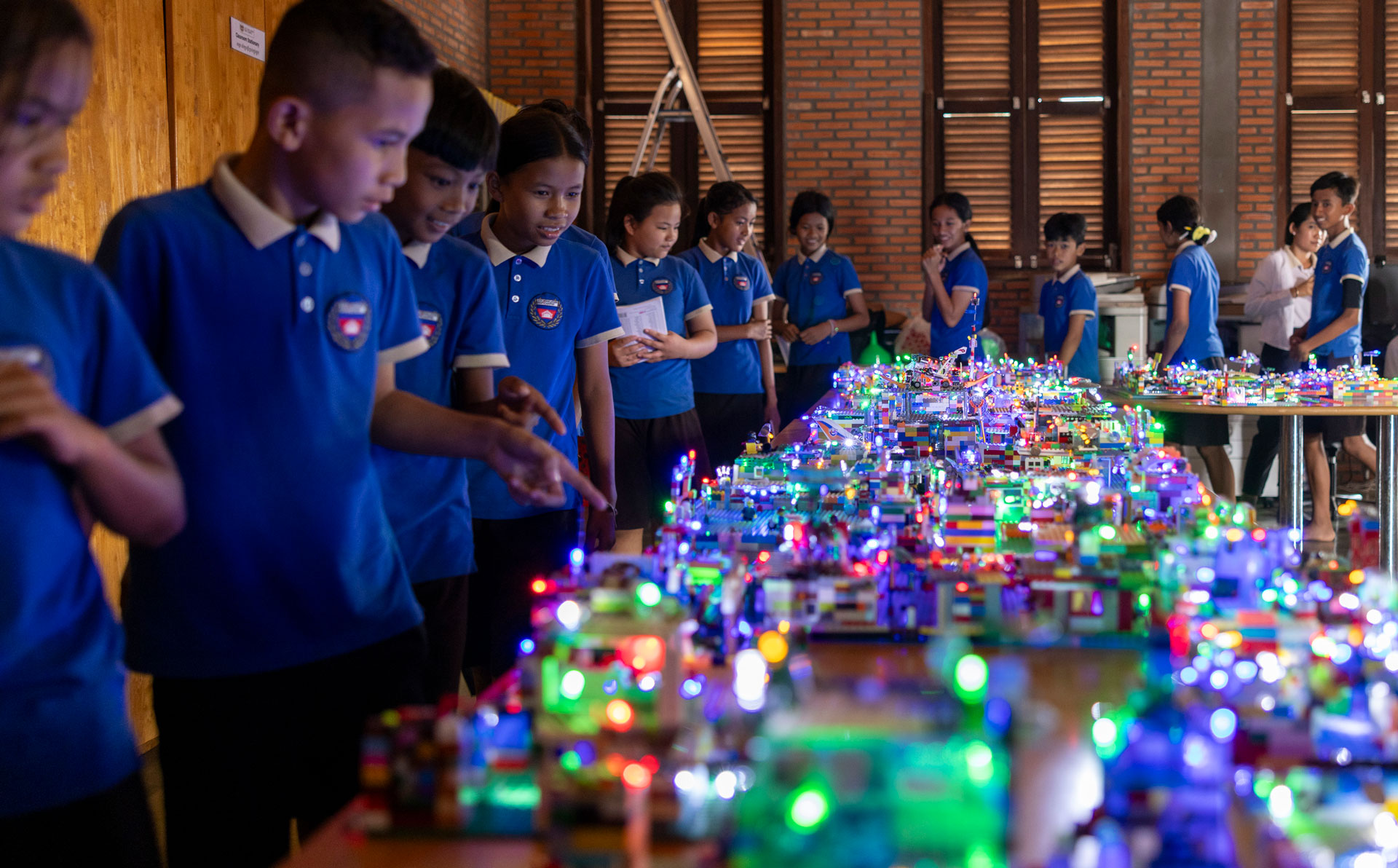 Schulkinder bauen an einer beleuchteten LEGO-Stadt.