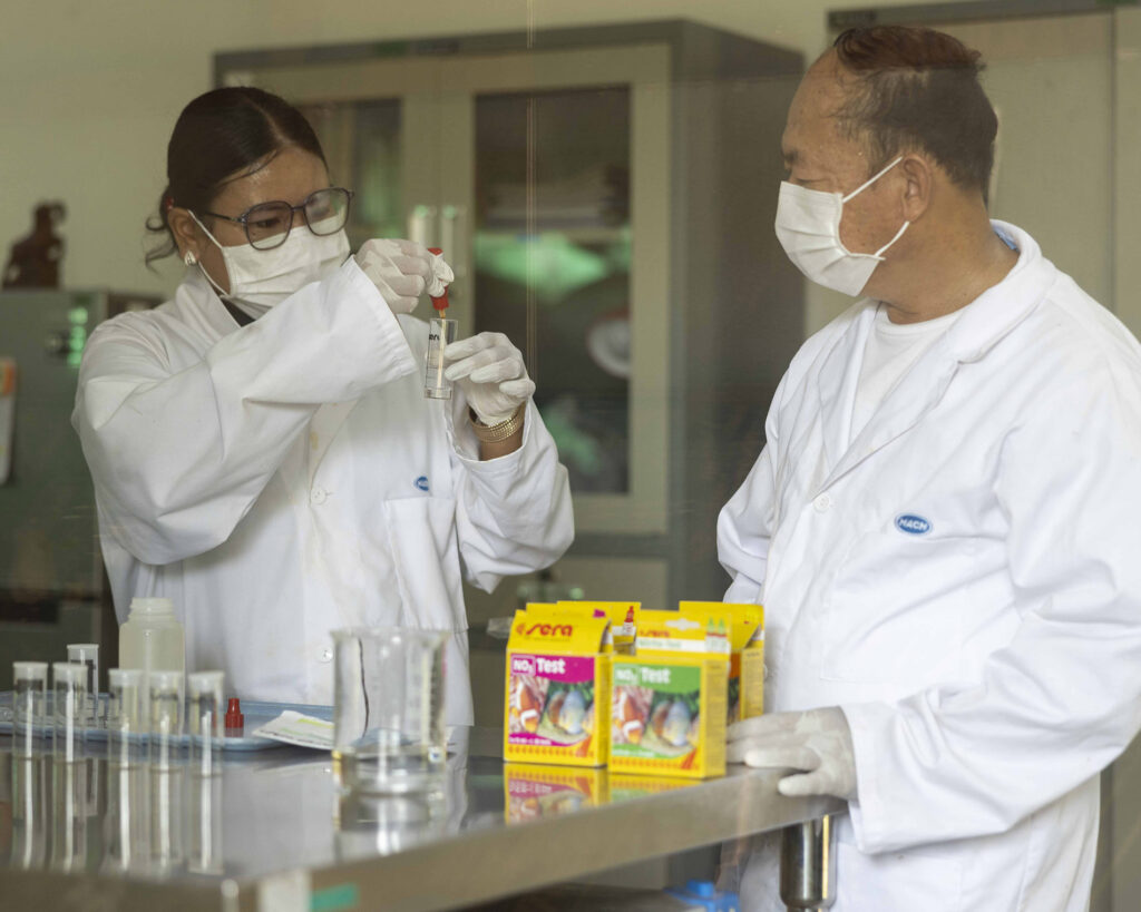 Two people in protective clothing working in a laboratory.